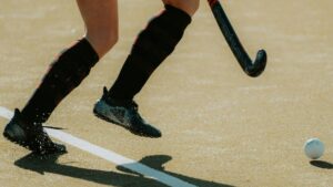 Close-up shot of a field hockey player dribbling a ball on a sunny day, showcasing movement and precision.